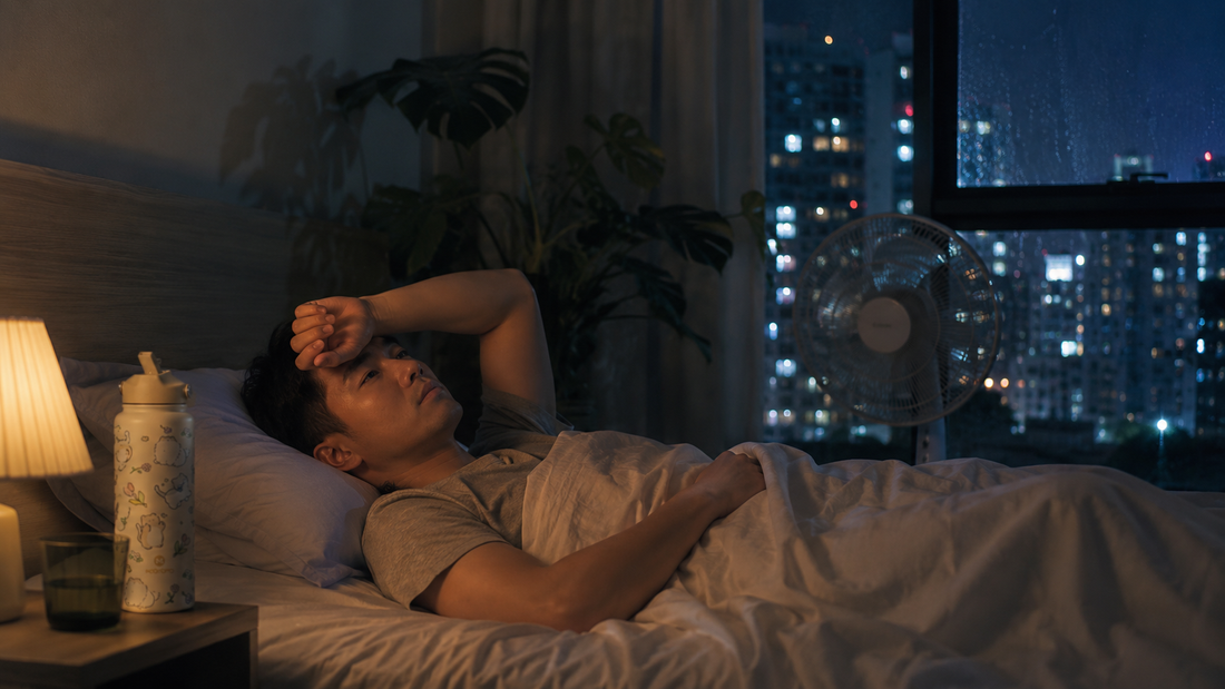 Sleepless man resting in warm humid bedroom during tropical summer night with soft fan airflow and city lights